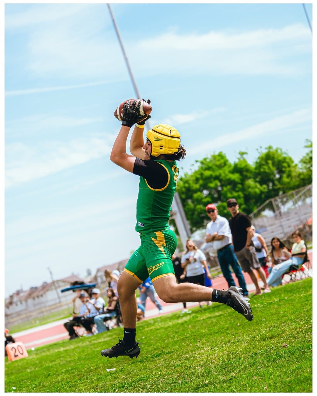 Program receiver in green kit catching a ball at full extension