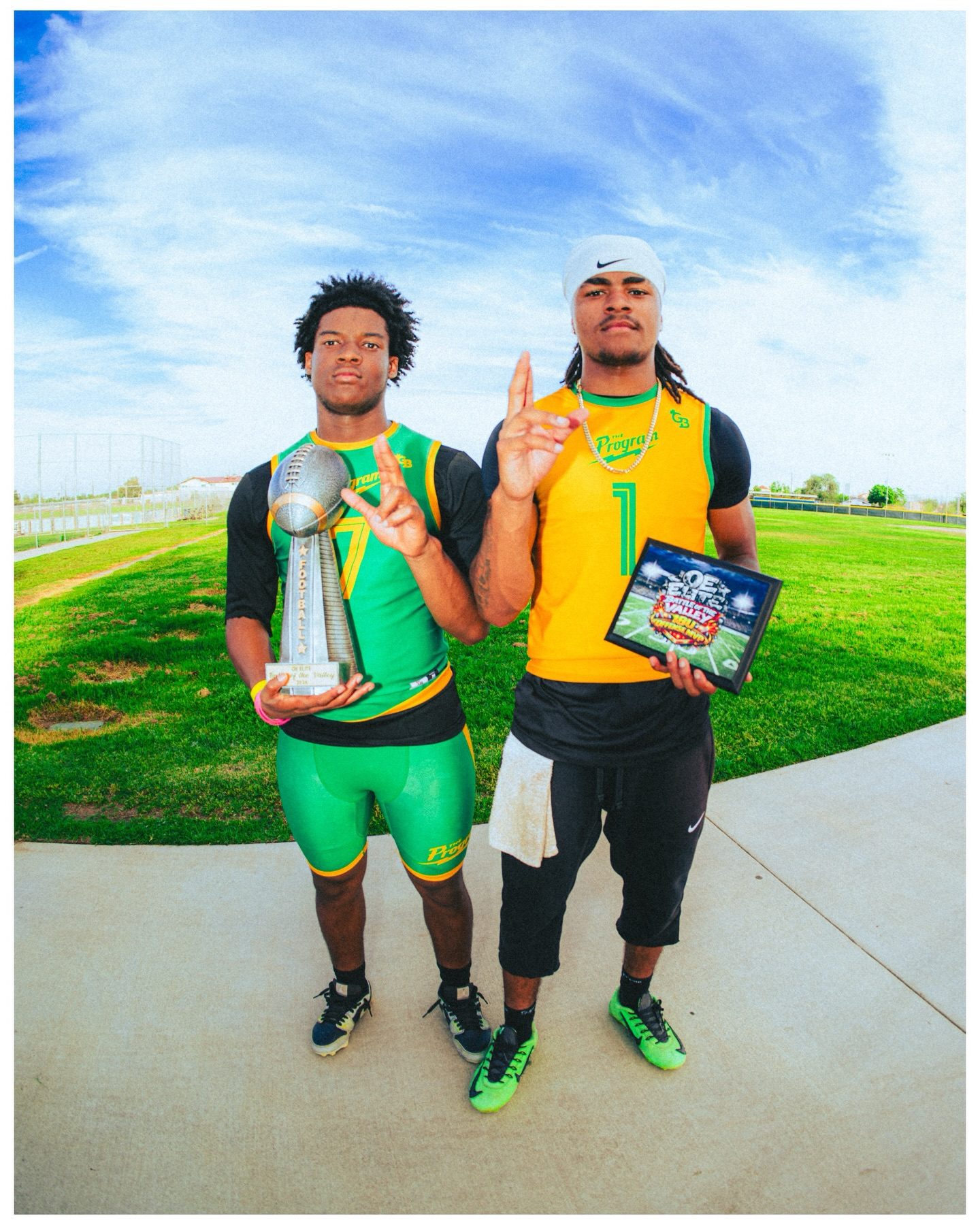 Two Program athletes holding the Battle of the Valley trophy and an MVP plaque