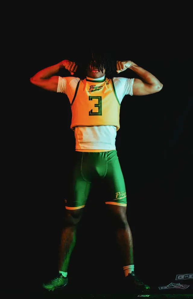 Program athlete number 1, crowned, crouched with palms up over money on the floor