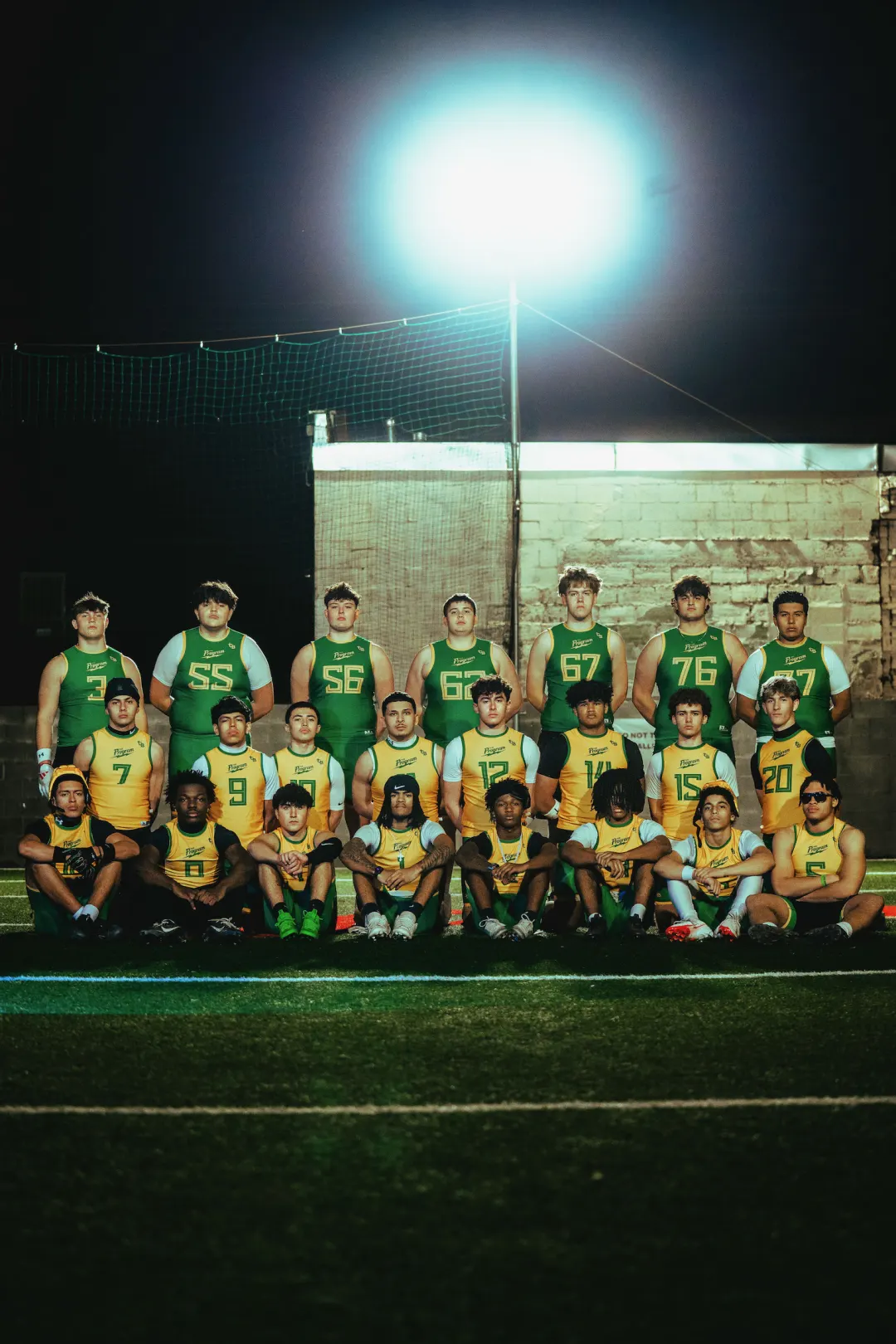 The full Program varsity roster lined up in green and gold at night