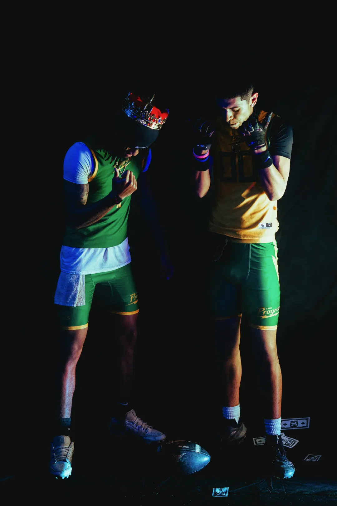 Two Program athletes, one crowned in green and one in gold, heads bowed over the ball
