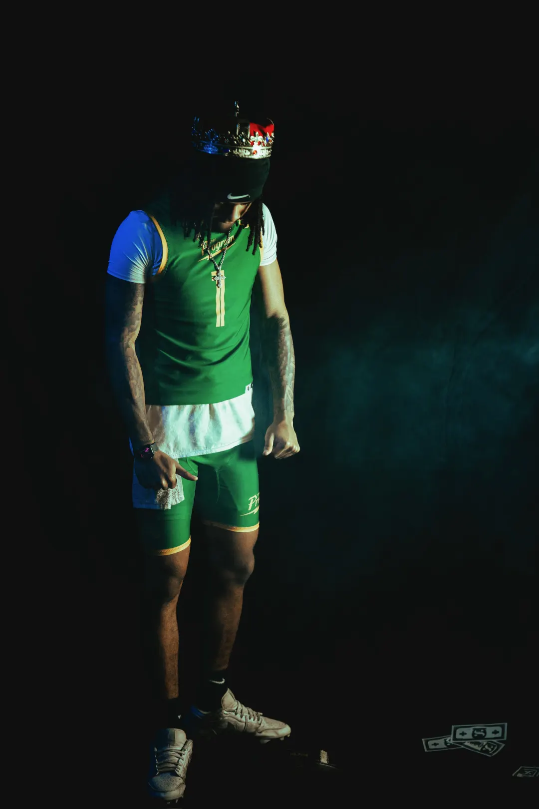 Program athlete number 1 in green, crown over a black skull cap, head bowed