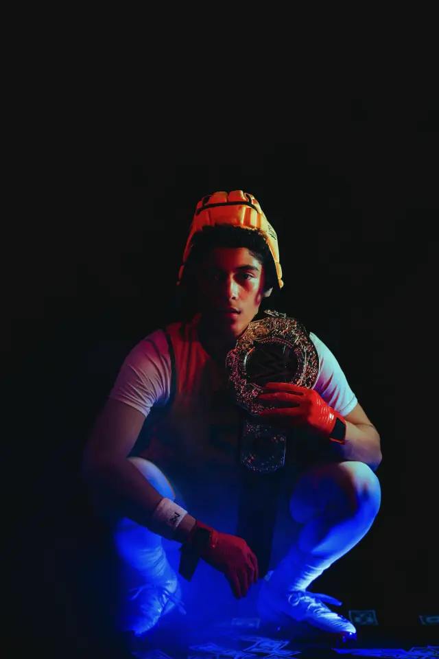 Program athlete crouched with a championship belt over his shoulder