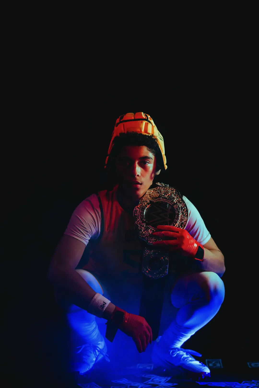Program athlete crouched with a championship belt over his shoulder