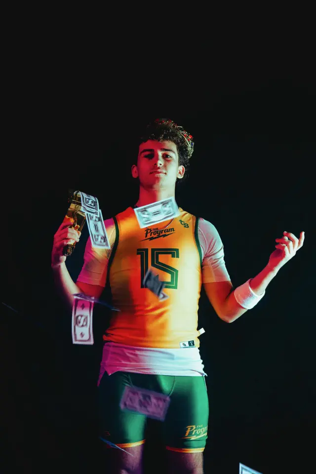 Program athlete number 15 wearing a crown, holding a gold trophy while bills fall