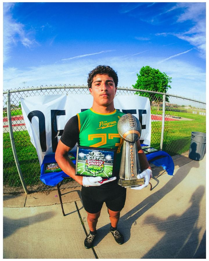 Program athlete holding the Battle of the Valley trophy and 18U MVP plaque