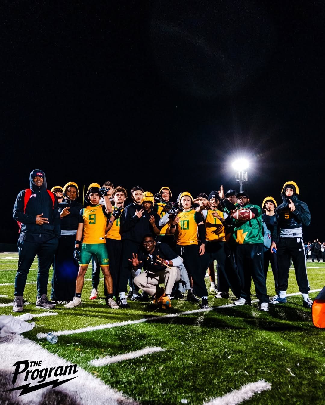 The Program squad and coaches on the field under stadium lights