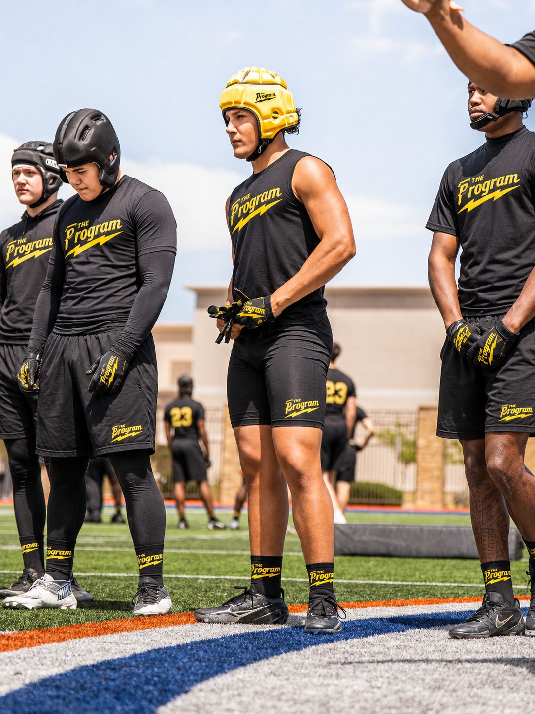 Program athletes in blackout kit and padded headgear waiting on the sideline