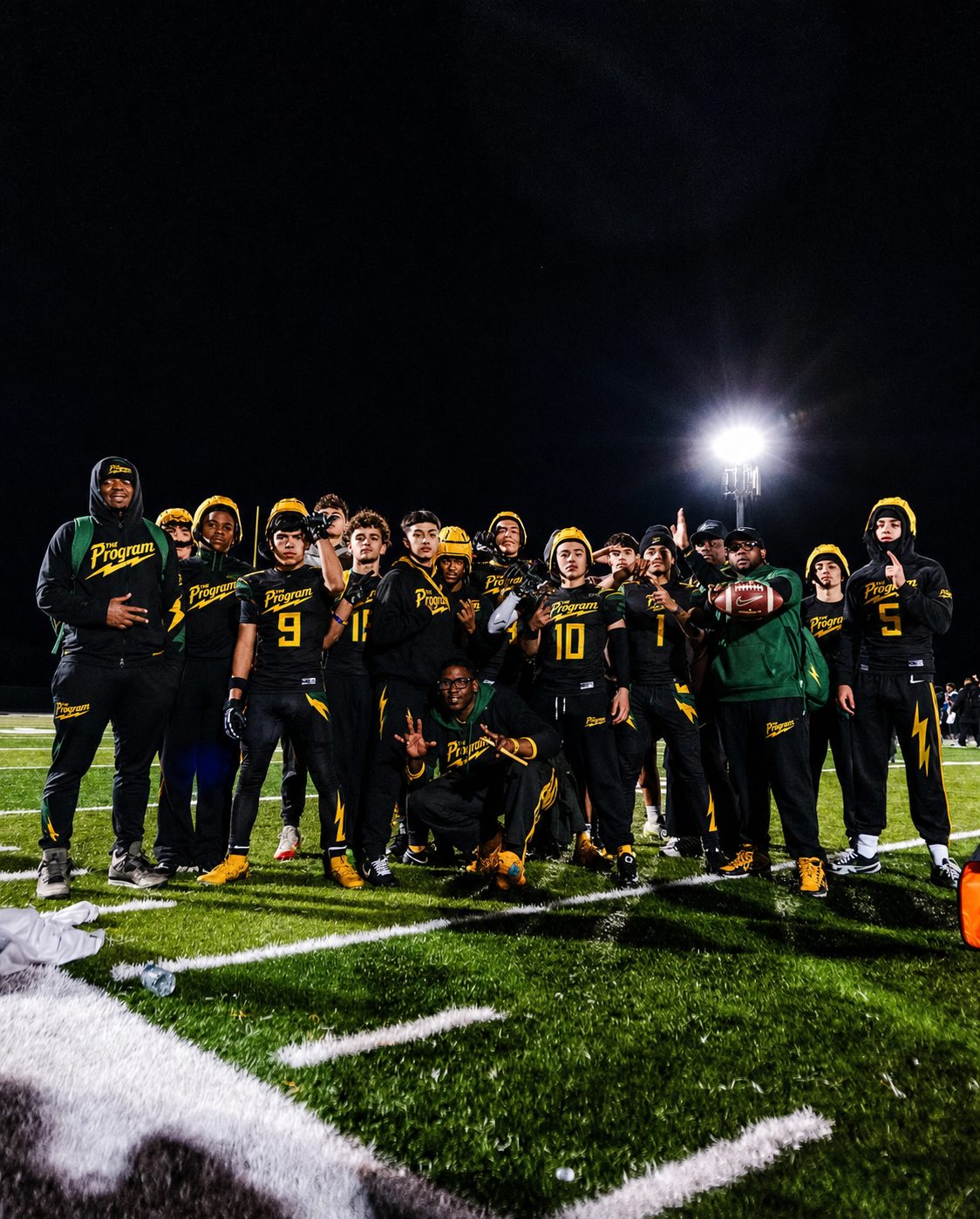 The full Program roster and staff gathered on the field at night