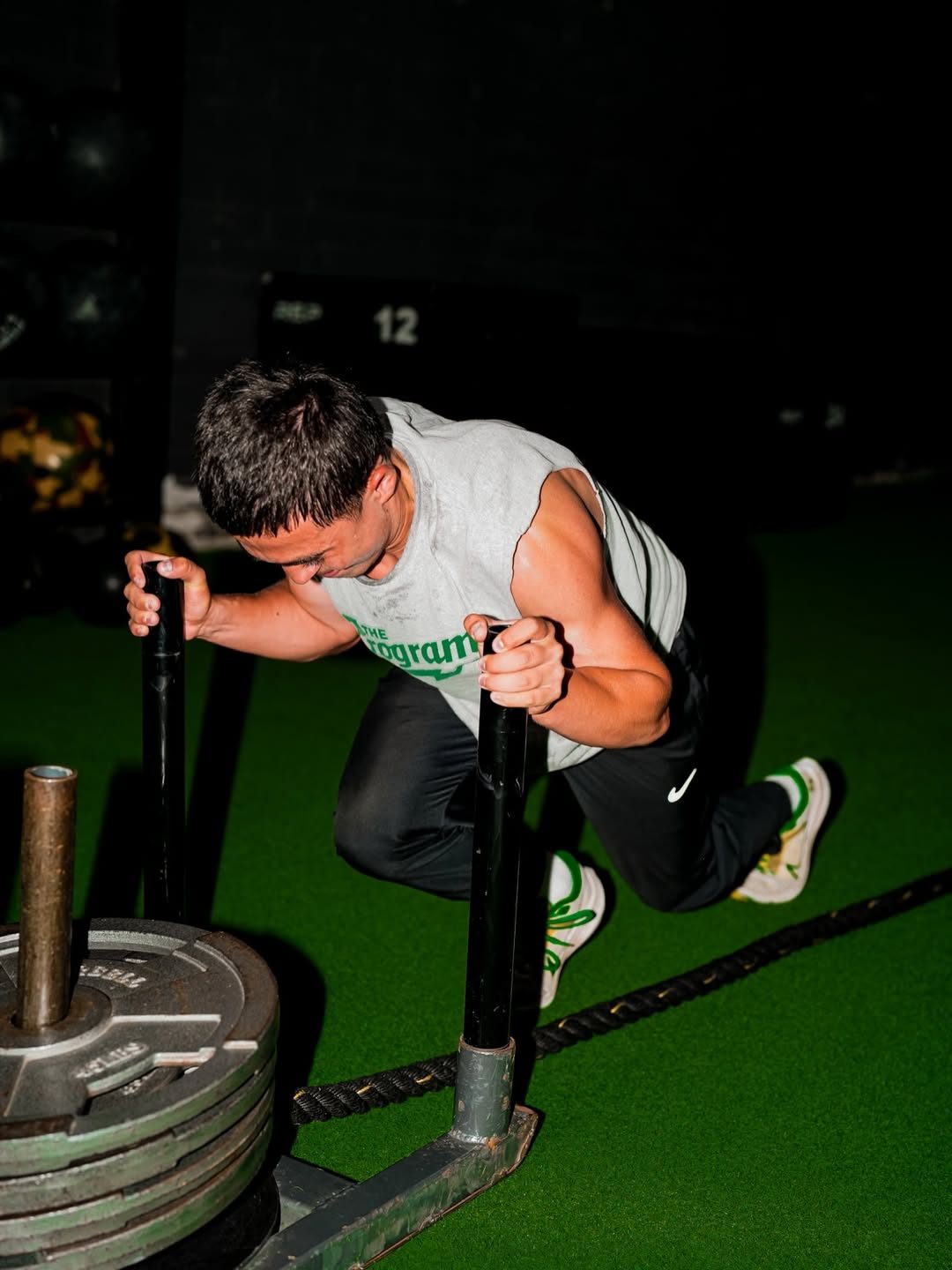 Program athlete driving a loaded sled during a strength session